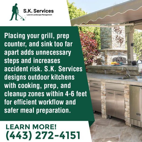 Large outdoor kitchen built with stone base cabinets, stainless steel appliances, a sink, and an outdoor fireplace/pizza oven in the background, all under a covered patio structure. S.K. Services designs zones (cooking, prep, cleanup) within 4-6 feet for efficient workflow and safer meal prep.